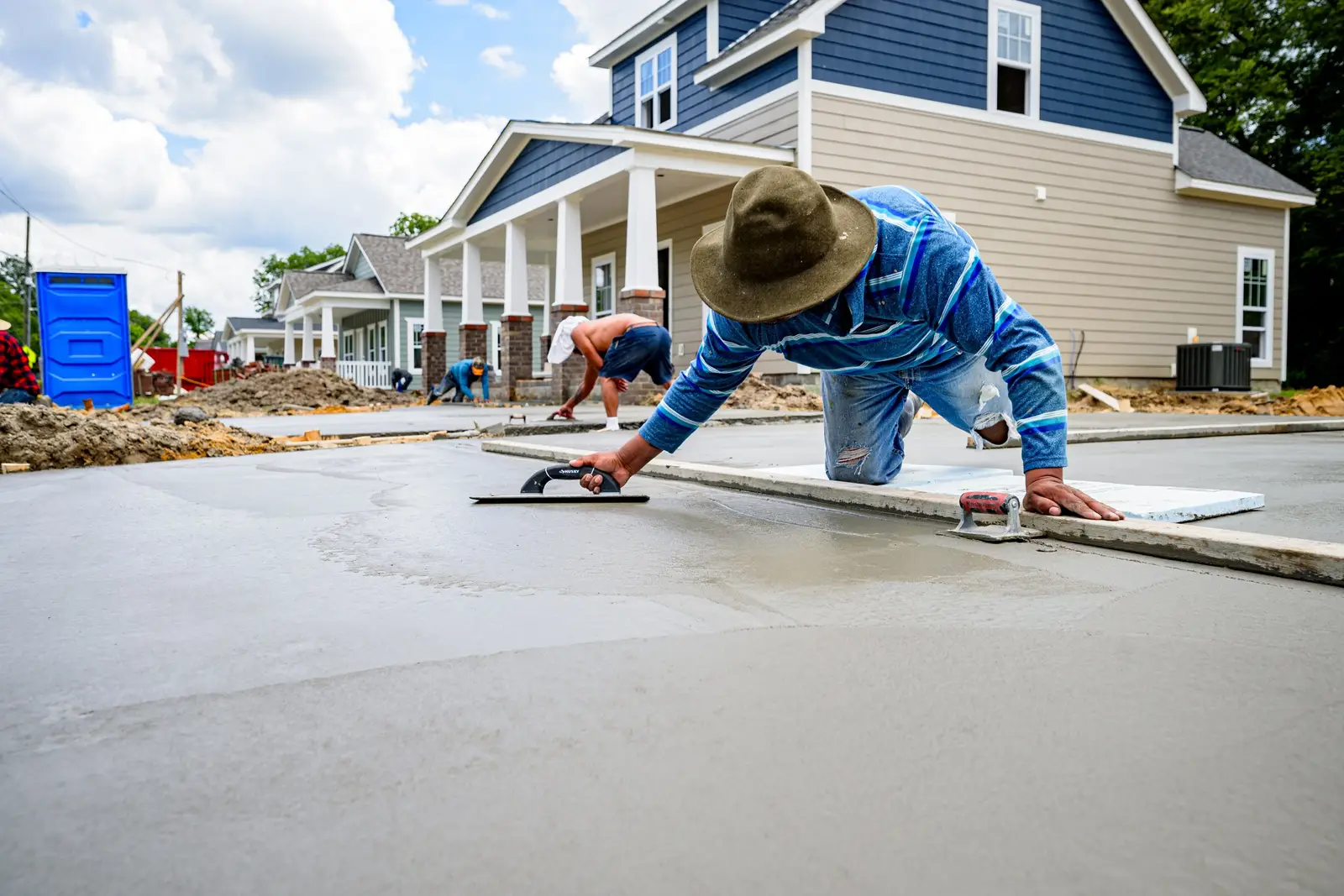 Concrete finisher hand-troweling a fresh sidewalk in front of a new home in the Cedar Hill, TX area